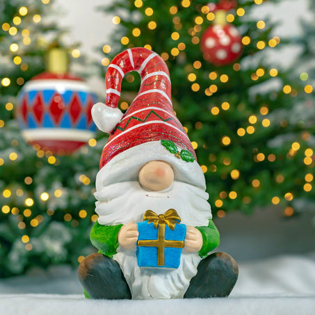 Christmas Garden Gnome Sitting with Gift and Red Striped Hat 